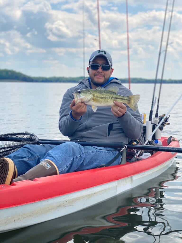 Angler holding a bass while kayak fishing